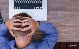 KI generiert - Gestresster Mann sitzt mit den Händen am Kopf vor einem Laptop.